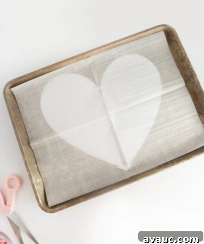Printed heart template placed on a cookie sheet under parchment paper
