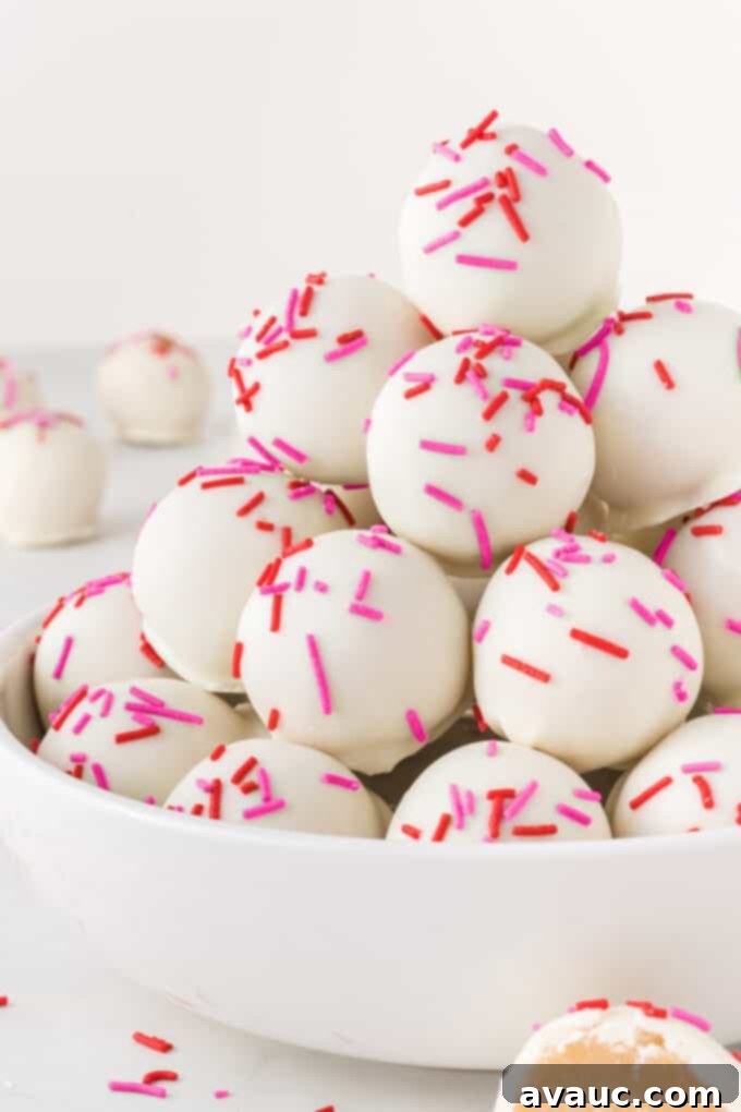 Valentines Day Sugar Cookie Truffles 12 A bowl overflowing with beautifully decorated sugar cookie Valentine truffles, featuring a mix of red, pink, and white sprinkles, inviting you to grab one.