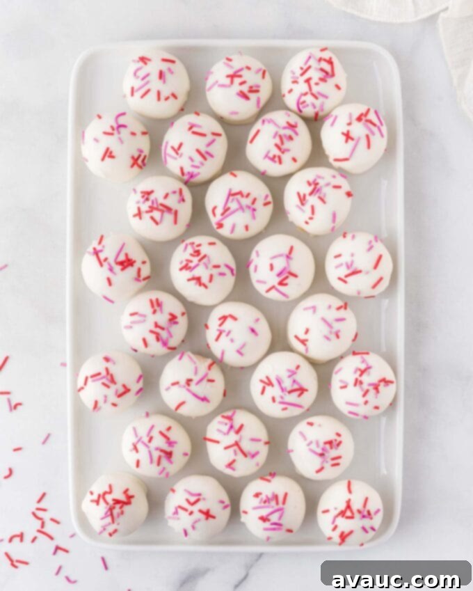 Valentines Day Sugar Cookie Truffles 3 A tray filled with an abundance of sugar cookie Valentine truffles, each one perfectly dipped and decorated, ideal for sharing at parties or as gifts.