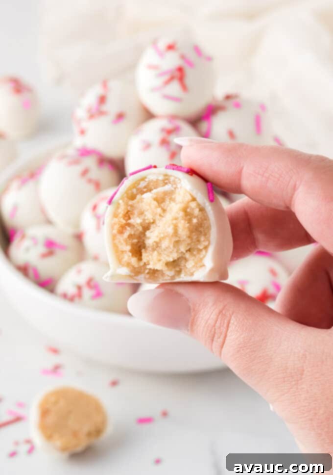 Valentines Day Sugar Cookie Truffles 4 A hand holds a sugar cookie Valentine truffle with a bite taken out, revealing the soft, delicious interior and the crunchy white chocolate coating.