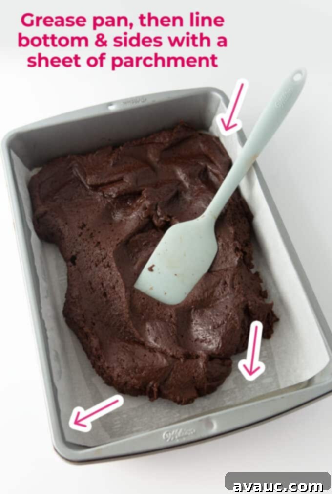 Spreading cosmic brownie batter into a parchment-lined 9x13 pan