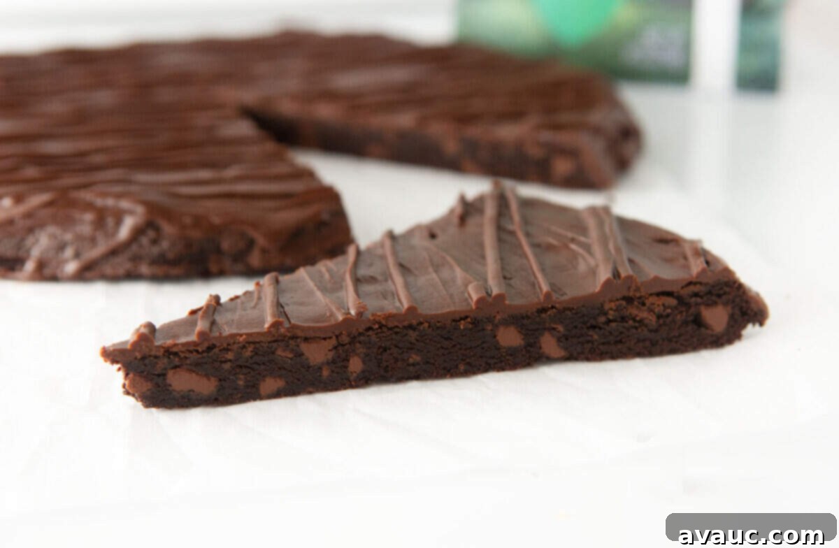 slice of giant thin mint cookie cake with a fork, showing the thick, chewy texture and chocolate coating