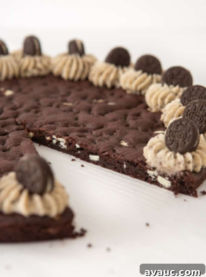 Oreo Dream Cake 3 Close-up view of an Oreo pizza cookie cake with one slice carefully removed, revealing the dense, chewy interior.