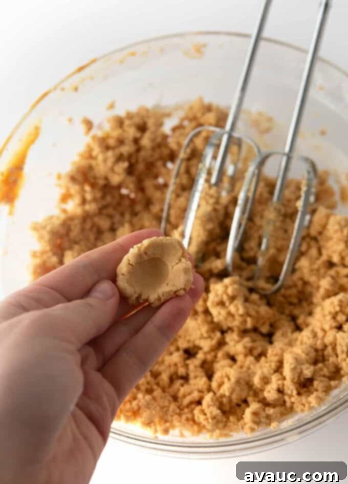 Irresistible Homemade Peanut Butter Eggs 5 Bowl of homemade peanut butter egg dough with a thumb pressing into it to show its play-doh like, creamy texture