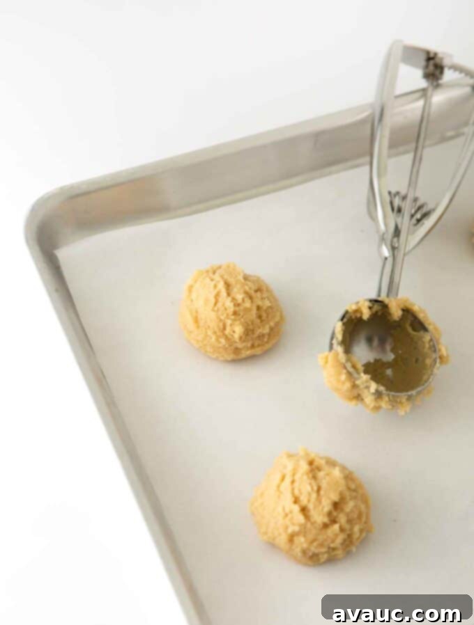 Mini M&M Chewy Bites 6 Scooped cookie dough balls on a parchment-lined baking sheet, ready for the oven.