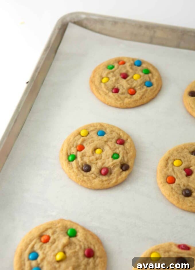 Mini M&M Chewy Bites 7 Hot cookies with mini M&Ms being pressed into them, showcasing the vibrant colors.