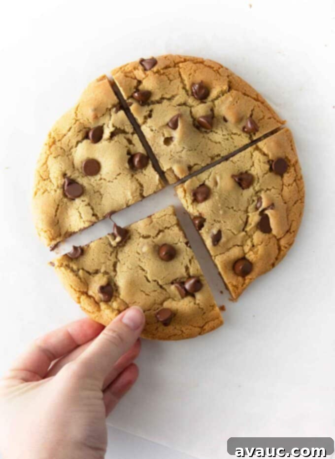 One Epic Chocolate Chip Cookie 9 Giant chocolate chip cookie served whole on a plate with a glass of milk.