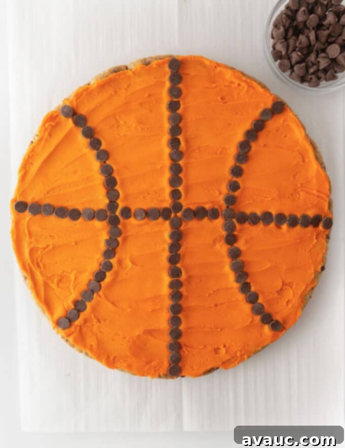 Fully decorated basketball cookie cake with bright orange frosting and perfectly placed chocolate chip seams