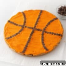 Top-down view of a fully decorated basketball cookie cake with orange frosting and chocolate chip seams