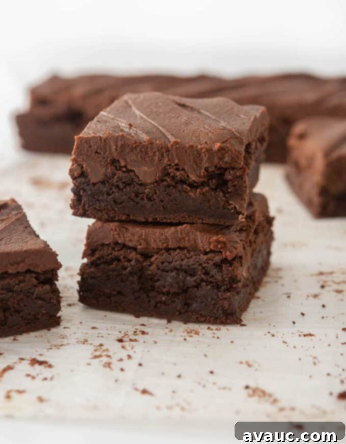 A close-up of a brownie corner with thick, glossy chocolate frosting.