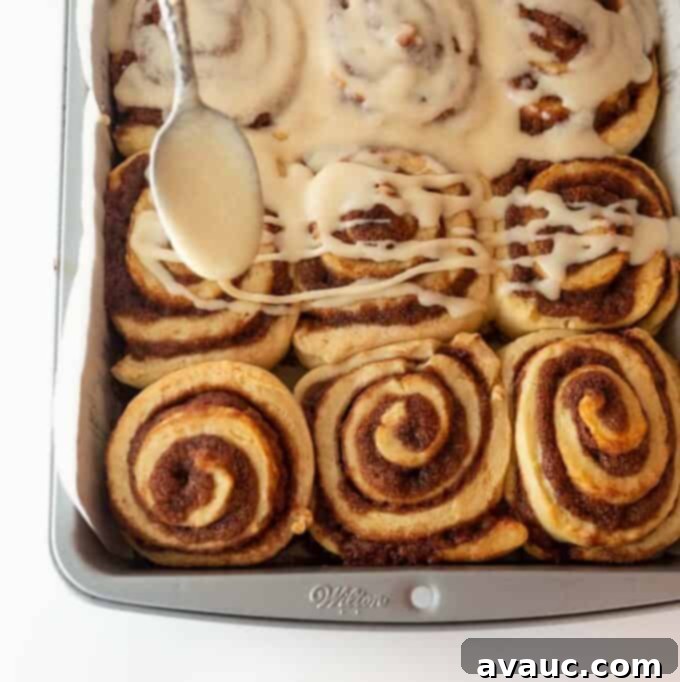 Mixing ingredients for cinnamon roll icing in a bowl with a hand mixer, showing the creamy texture.