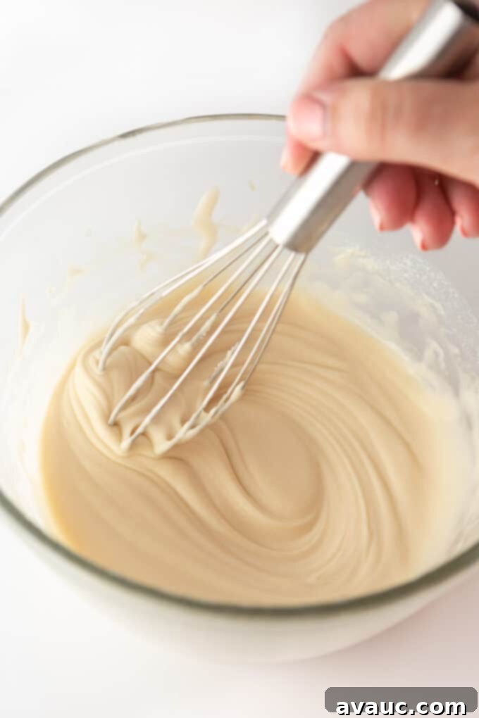 A bowl of freshly made vanilla cinnamon roll icing, ready to be drizzled.