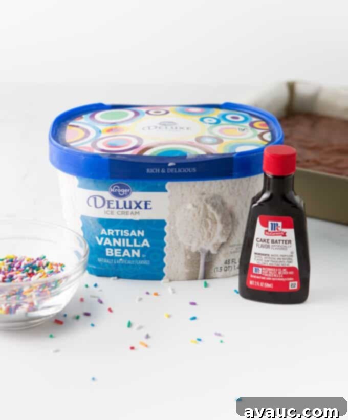 Three ingredients for cake batter ice cream: a tub of vanilla ice cream, a bottle of cake batter extract, and a jar of rainbow sprinkles.