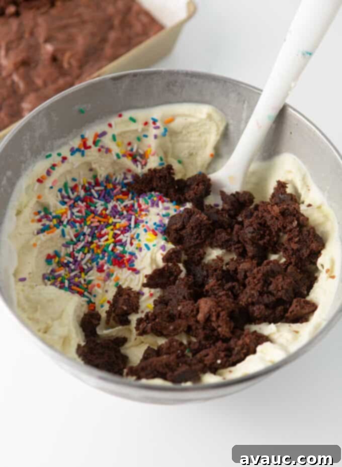 Bowl of finished cake batter ice cream with brownie pieces and colorful sprinkles mixed in.