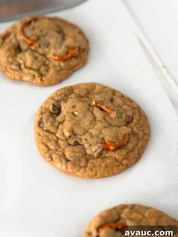 Close-up of a stack of freshly baked Kitchen Sink Cookies, showing melted chocolate, gooey caramel, and pretzel pieces.
