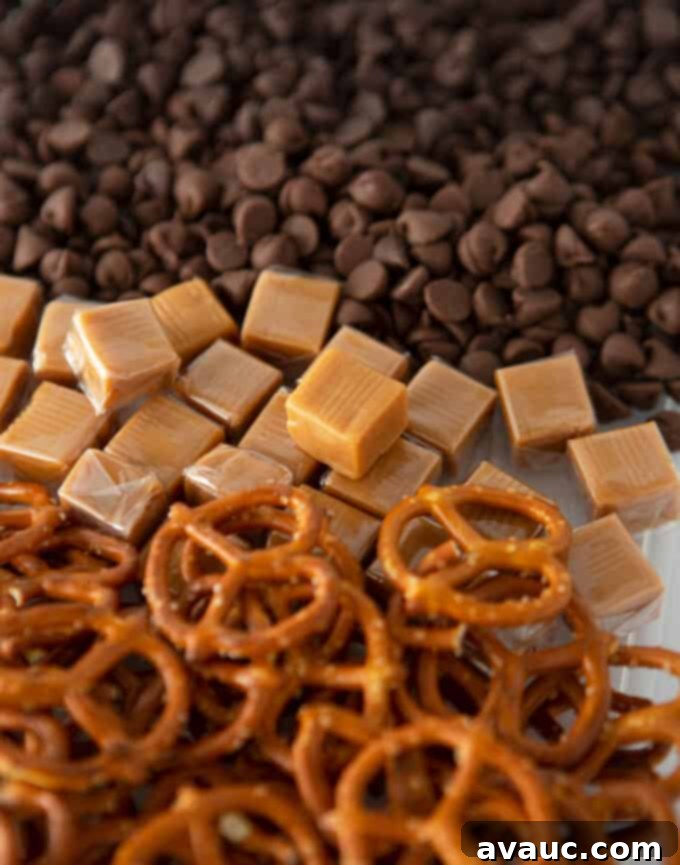 Various Kitchen Sink Cookie ingredients laid out, including semi-sweet and milk chocolate chips, pretzels, and chopped caramel.