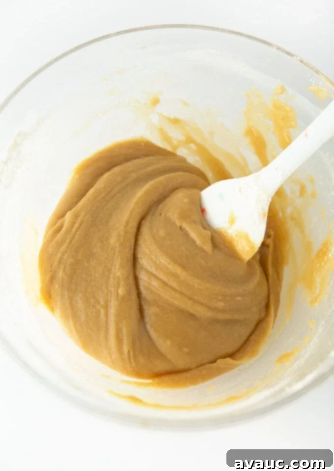 Cookie dough being mixed with melted butter and sugars in a bowl.