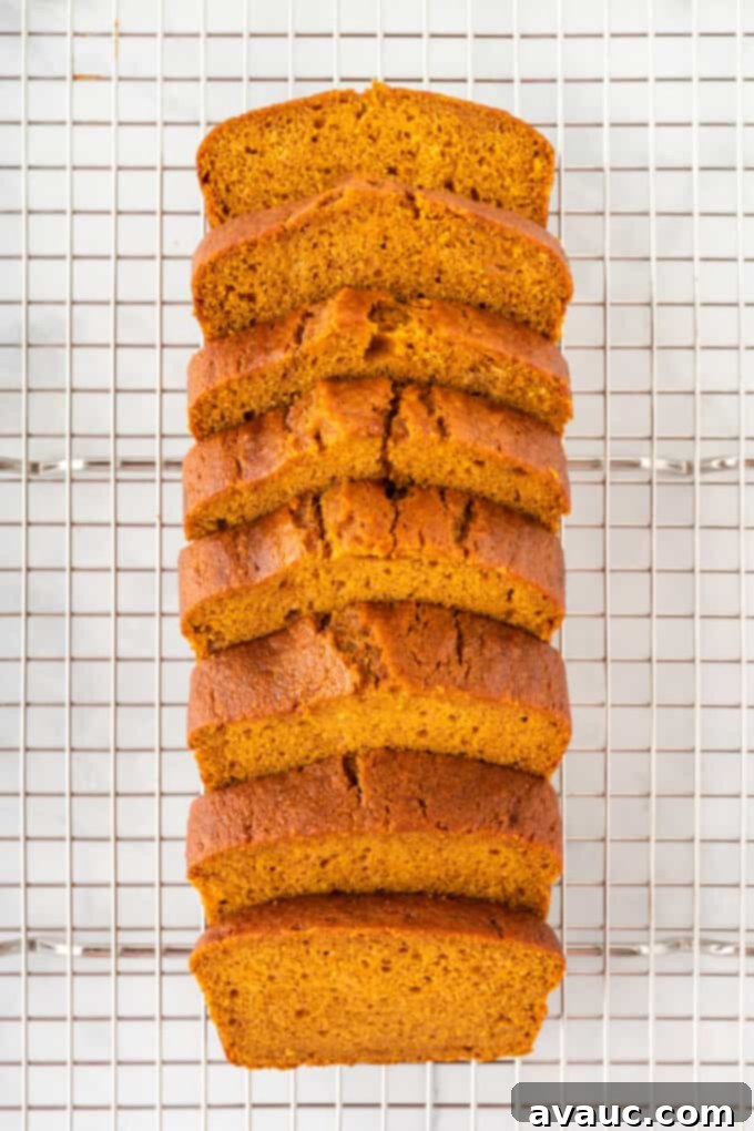 Delicious thick slices of freshly baked pumpkin bread, neatly stacked on a wire cooling rack, awaiting serving and indulgence.