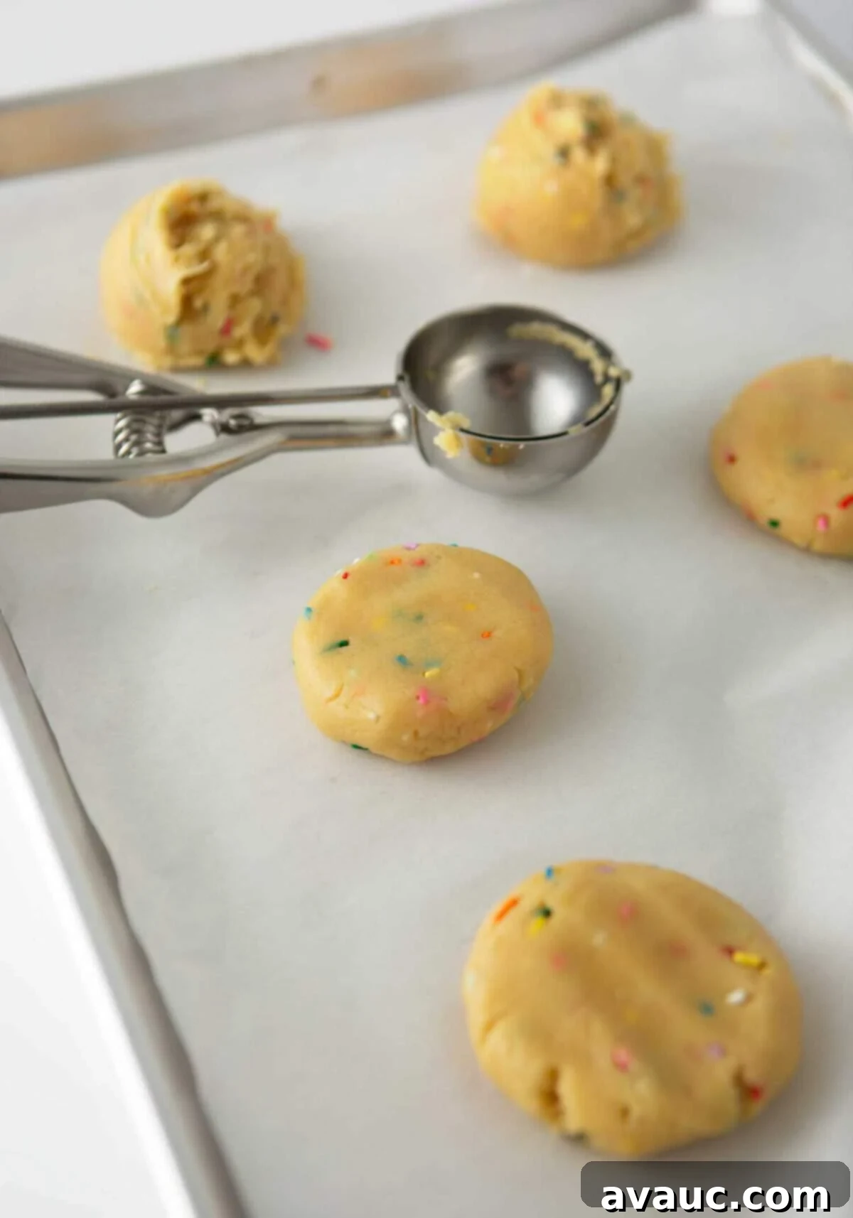 Frosted Funfetti Cookies 6 scooped cookie dough on pan with metal cookie scoop