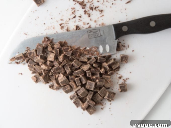 One Bowl Chocolate Chip Bliss 6 A knife chopping chocolate chunks on a cutting board.