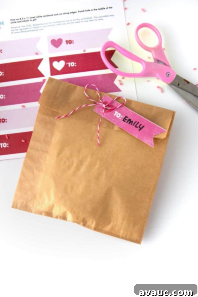 Free Valentines Day Tag Printables 3 Woman's hands tying a free printable Valentine tag to a cellophane bag filled with homemade cookies, illustrating easy gift packaging.