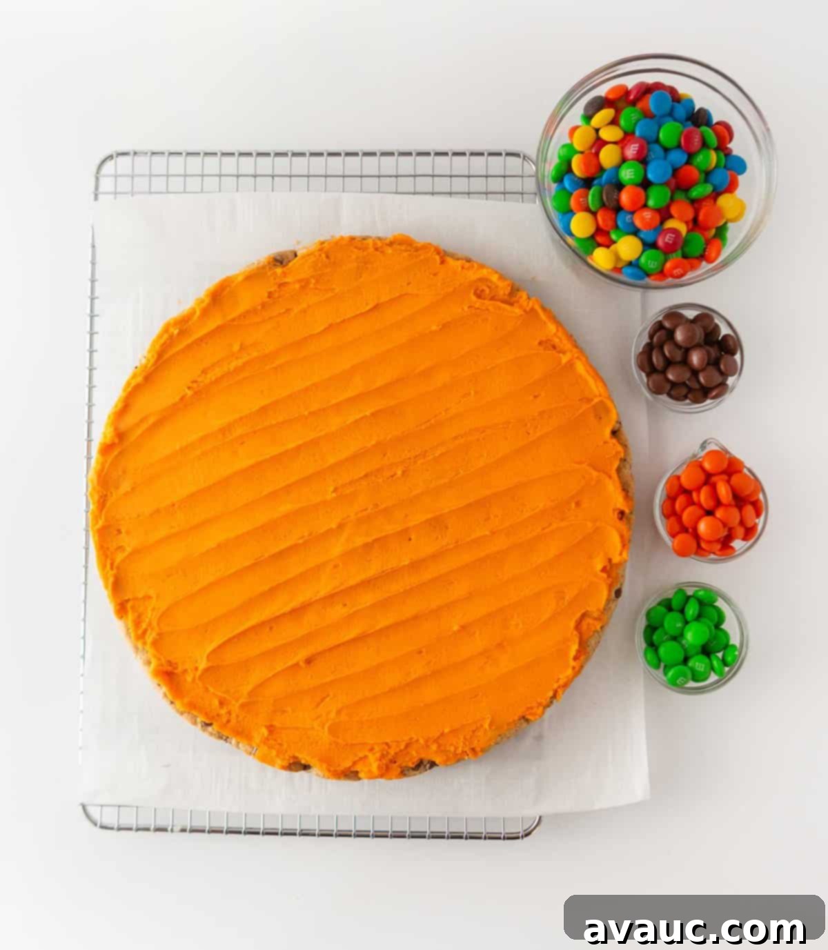 Spooktacular Easy Pumpkin Cookie Cake 3 orange cookie cake on wire rack with bowls of m&m's