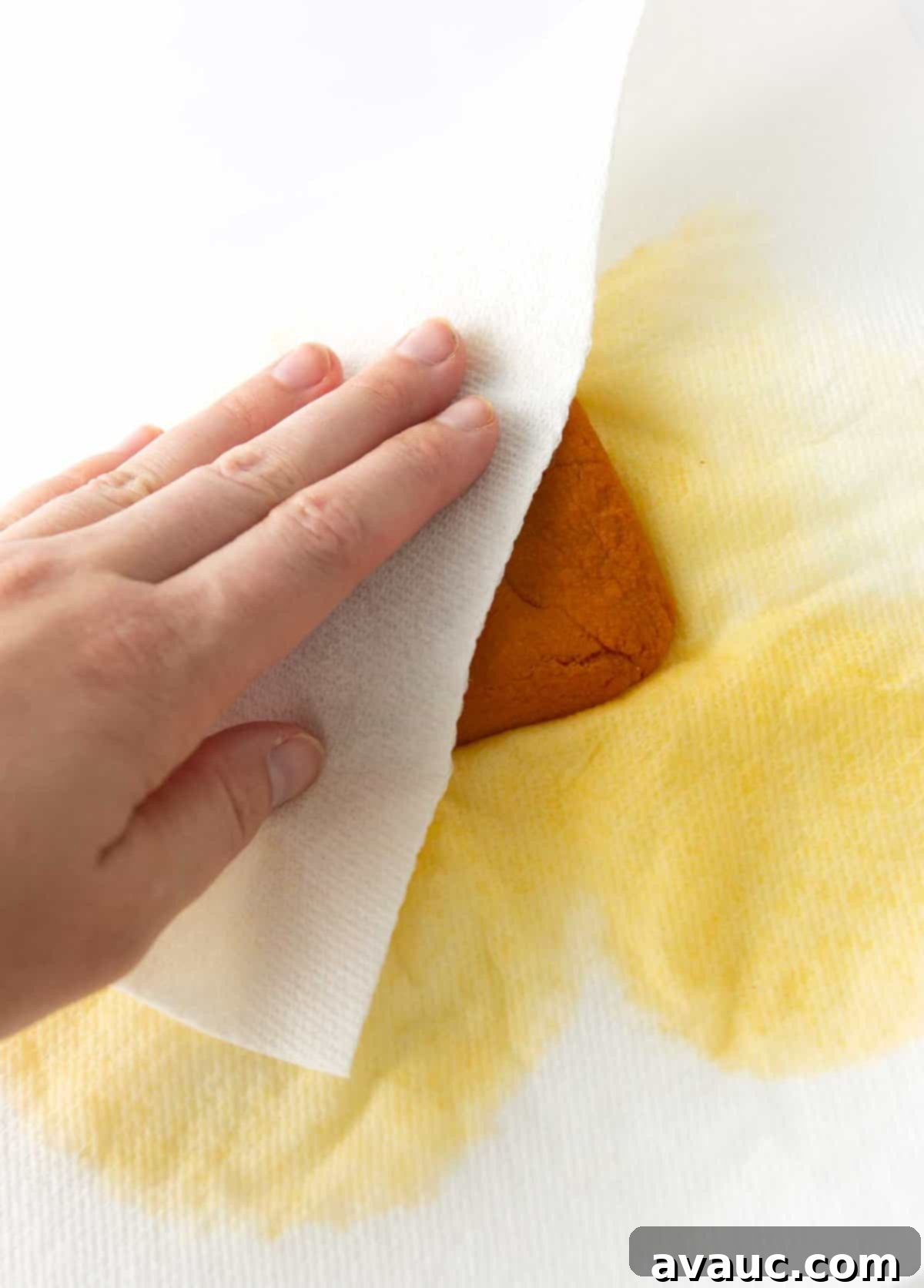 Initial stage of blotting water from pumpkin puree with paper towels, showing moisture being absorbed.