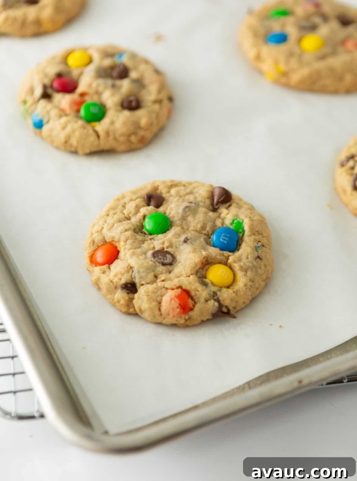 Freshly baked monster cookies on a baking pan, still warm from the oven, showing their perfect golden edges