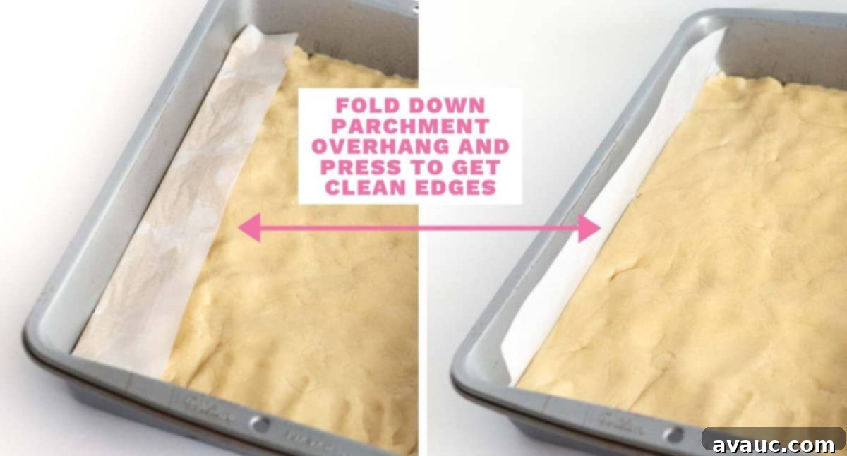Festive Christmas Tree Sugar Cookie Bars 15 A 9x13 pan of sugar cookie dough with parchment overhang, demonstrating how to press down the dough to achieve clean edges before baking.
