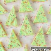 Festive Christmas Tree Sugar Cookie Bars 16 A festive array of green Christmas tree sugar cookie bars, adorned with colorful nonpareil sprinkles, neatly arranged in a 9x13 pan.