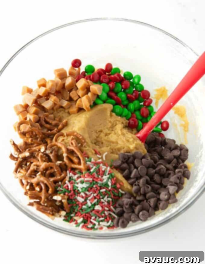 Festive Cookie Squares 6 Bowl of Christmas cookie dough with colorful mix-ins like pretzels, holiday M&M's, chocolate chips, and caramel before mixing.