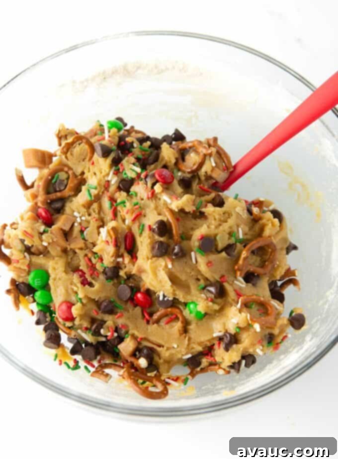 Festive Cookie Squares 7 Mixed bowl of Christmas cookie dough, showcasing pretzels, holiday M&M's, chocolate chips, and caramel perfectly integrated.