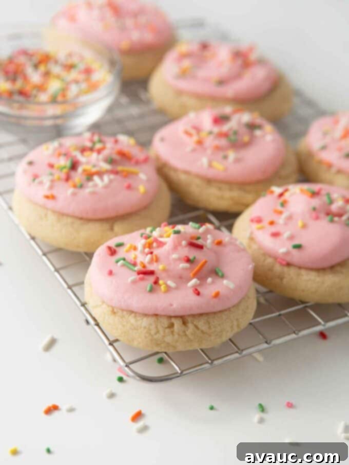 soft frosted sugar cookies on cooling rack with pink frosting and rainbow sprinkles