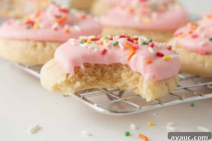 soft frosted sugar cookies with pink frosting and bite to show soft texture
