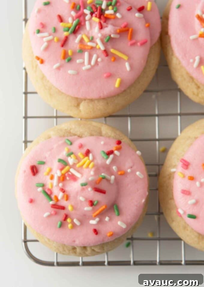 soft frosted sugar cookies on cooling rack with pink frosting and rainbow sprinkles