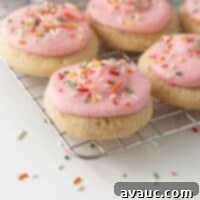 soft frosted sugar cookies on cooling rack with pink frosting and rainbow sprinkles