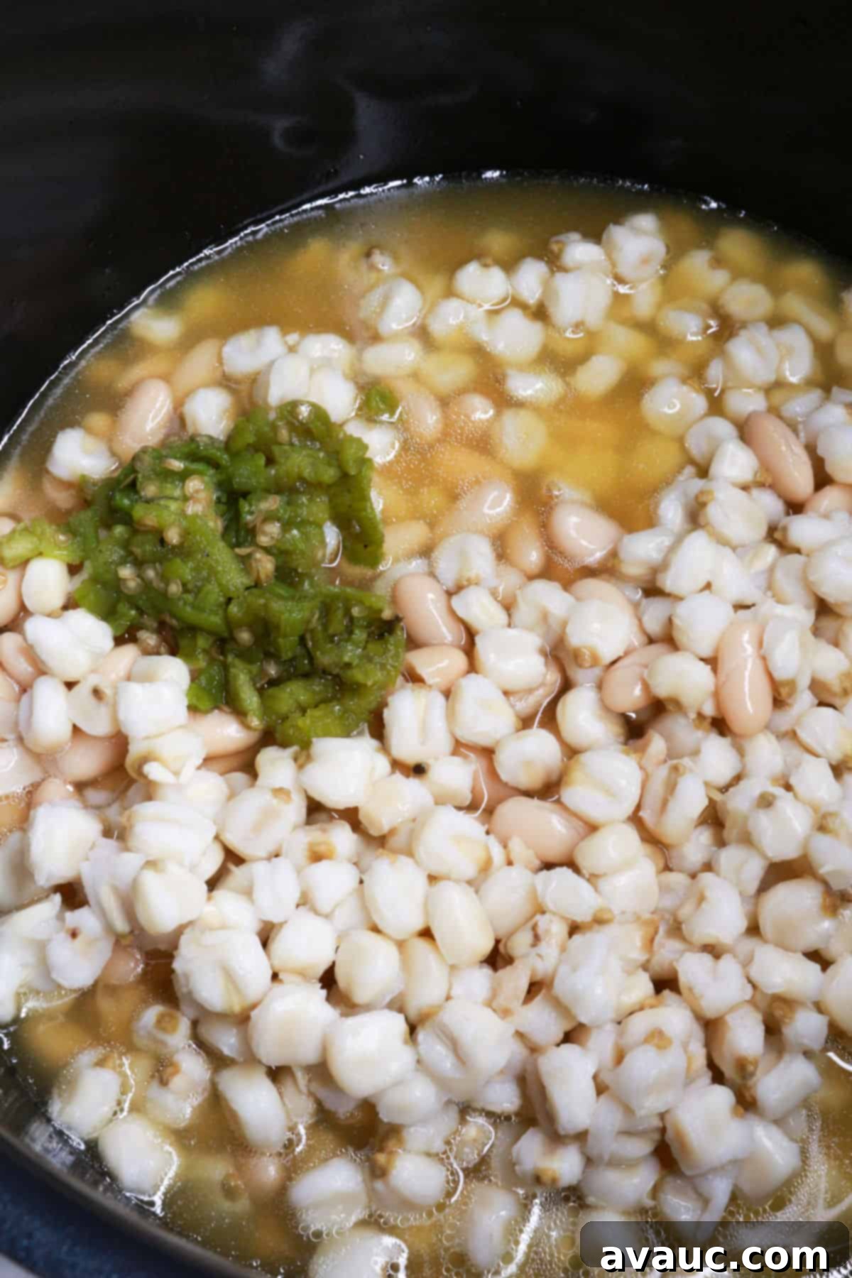 Foolproof White Chicken Chili with Hominy 6 A pot with hominy, white beans, diced green chiles, and broth