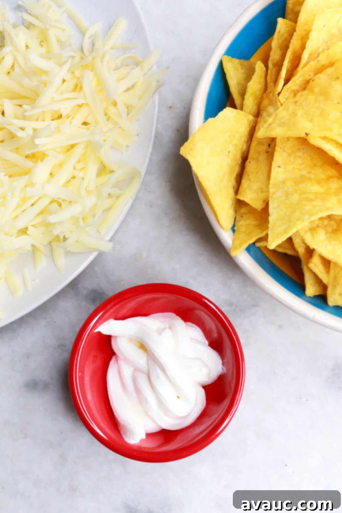 Foolproof White Chicken Chili with Hominy 7 A plate with shredded cheese, another with tortilla chips and a smaller one with sour cream