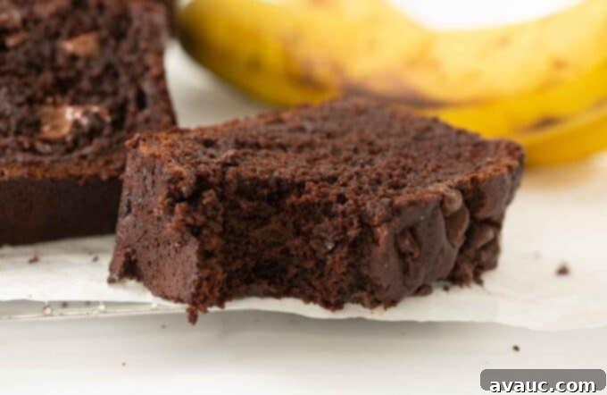 Close-up of a slice of double chocolate banana bread with a bite taken out, showing its moist texture and chocolate chips.
