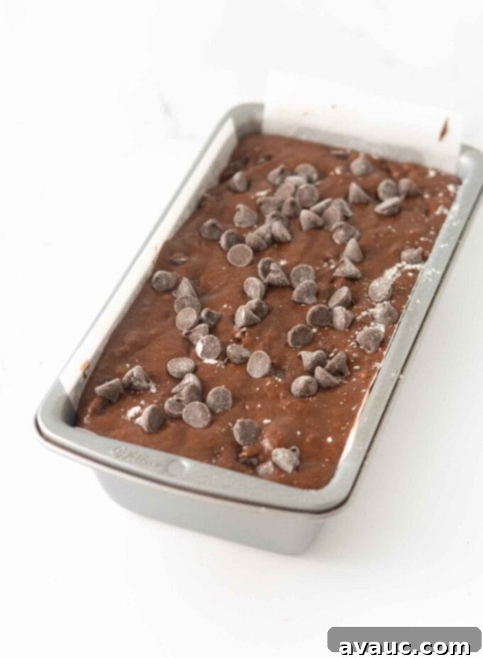 A loaf pan meticulously filled with double chocolate banana bread batter, topped with extra chocolate chips, ready for the oven.