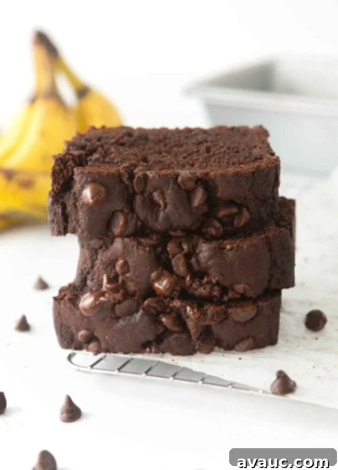 A stack of perfectly sliced double chocolate banana bread, showcasing its moist interior and generous chocolate chips.