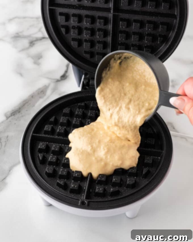 crispy waffle batter being poured into a hot waffle iron