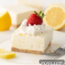 Easy No Bake Lemon Cheesecake Squares 15 square of no bake lemon cheesecake on plate with whipped cream and strawberry on top