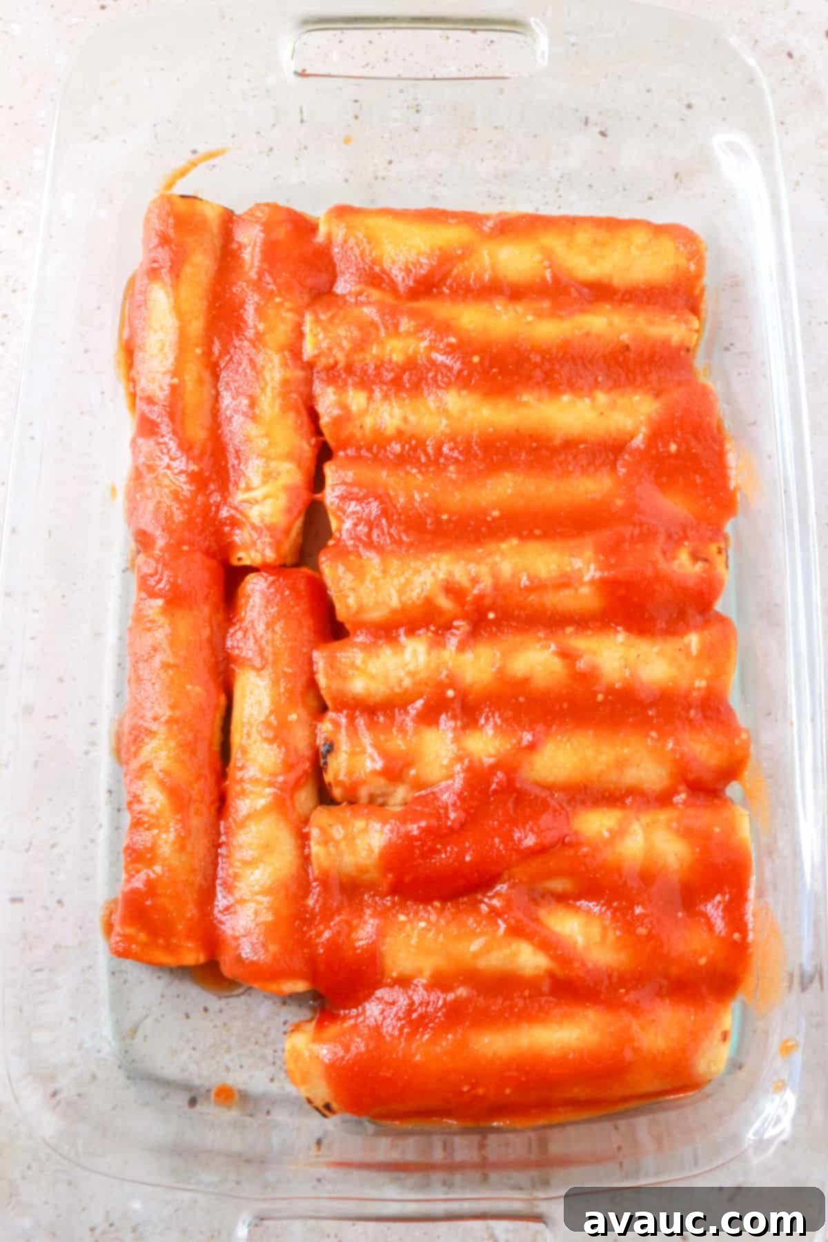 Ground beef entomatadas arranged in a baking dish with tomato sauce