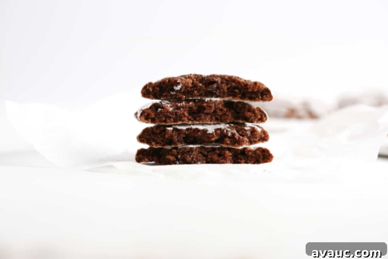 Stack of fudgy chocolate brownie cookies cut in half, showcasing their soft, chewy interior.