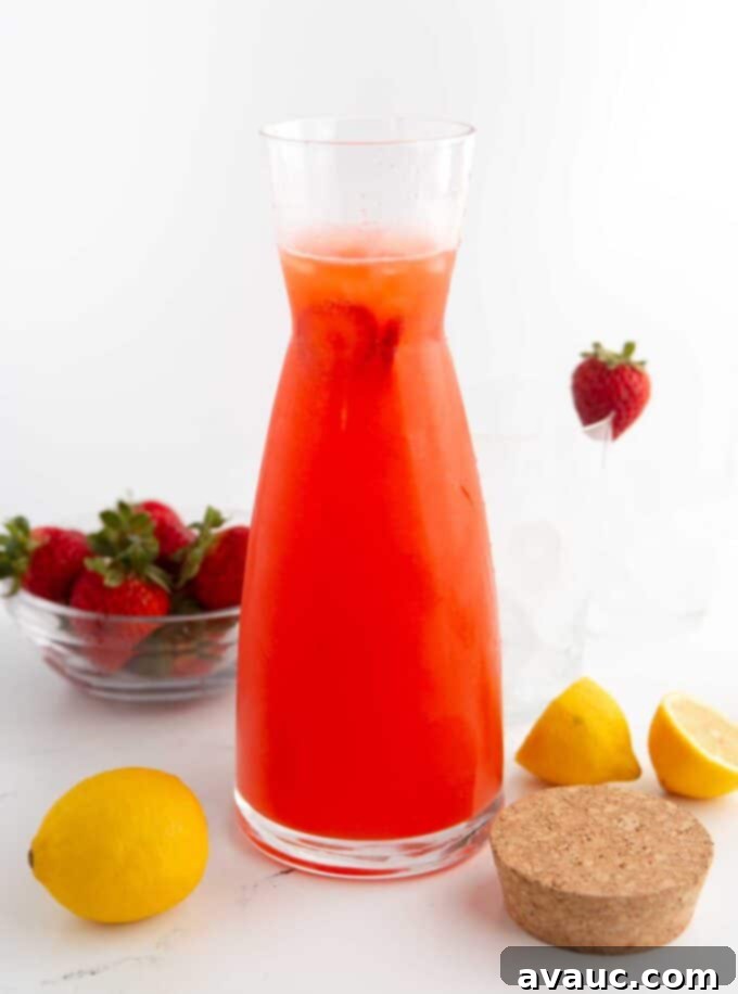 Easy Strawberry Lemonade 7 Glass pitcher filled with homemade strawberry lemonade, ready to be served.