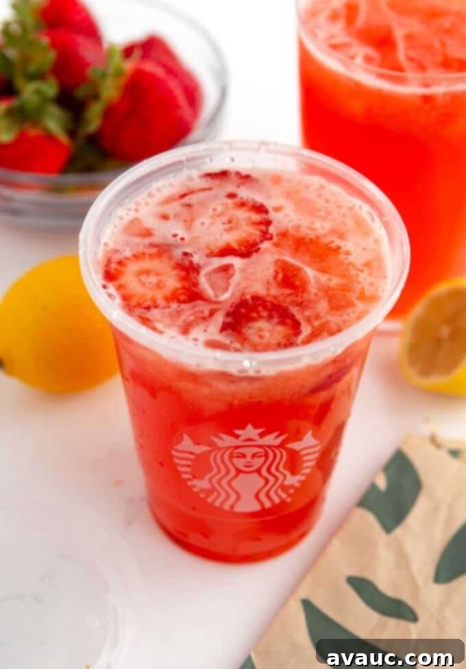 Easy Strawberry Lemonade 9 Two glasses of homemade strawberry lemonade, garnished with fresh fruit, on a bright table.