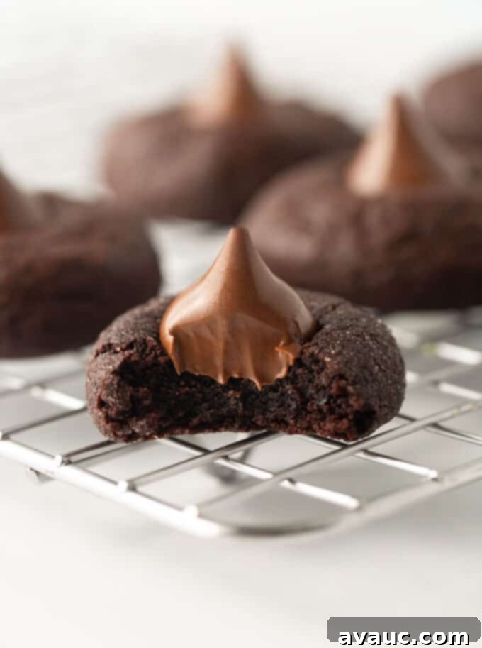Decadent Fudgy Chocolate Blossoms 3 A bite taken out of a chocolate blossom cookie on a wire rack, revealing its soft, chewy interior.