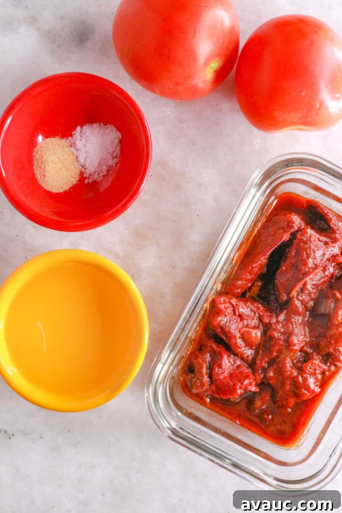 Ingredients for homemade chipotle salsa: Roma tomatoes, pinch bowl with garlic powder and salt, bowl with water and a container with chipotle peppers in adobo sauce