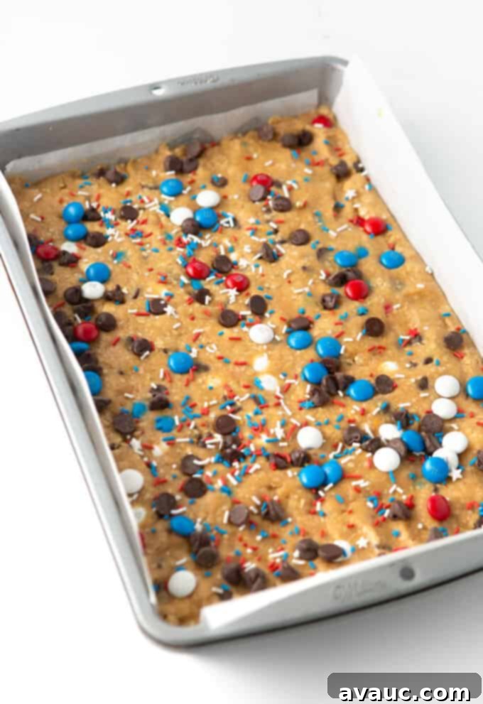 9x13 pan of unbaked fourth of july monster cookie bars with colorful sprinkles and candies on top